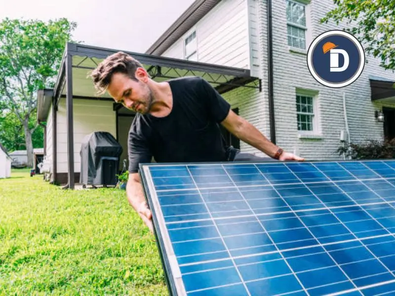 Hombre instalando un panel solar en el patio de su casa, promoviendo la eficiencia energética en el hogar.