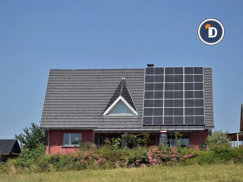 Casa con paneles solares en el techo, rodeada de vegetación en un entorno sostenible.